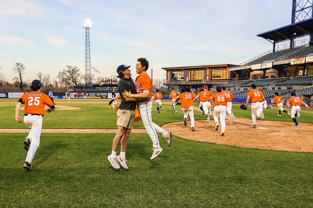 Two people chest bumping on a field.