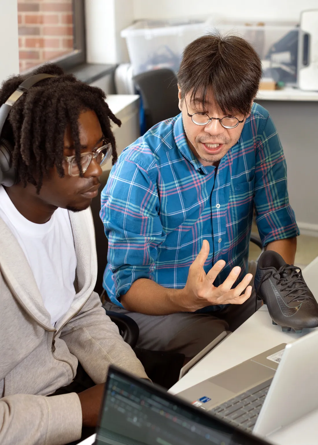 Two people sitting at desk looking at a computer.