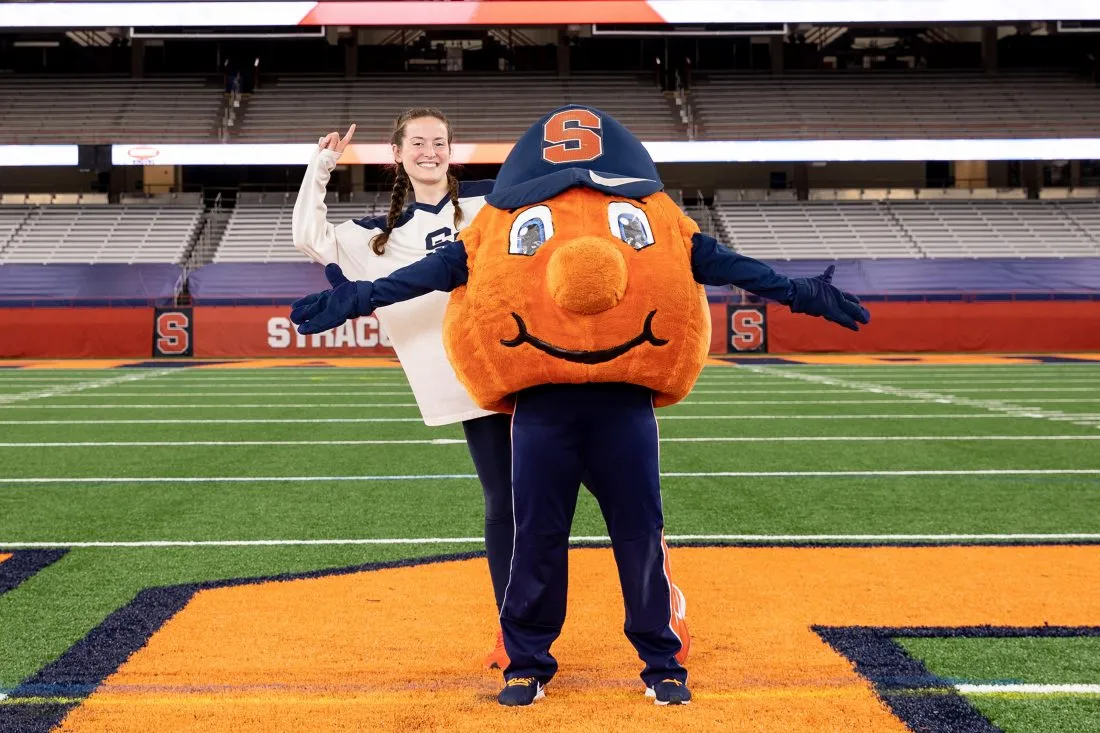 Caitlin Sanders poses for the camera standing behind Otto the Orange.
