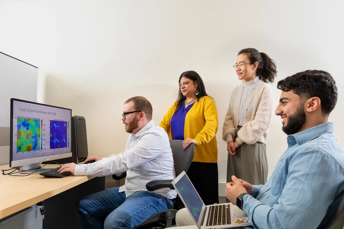 Shikha Nangia and students look onto computer screen.