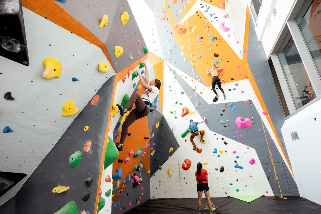 Four people climbing on multi-colored interior climbing wall.