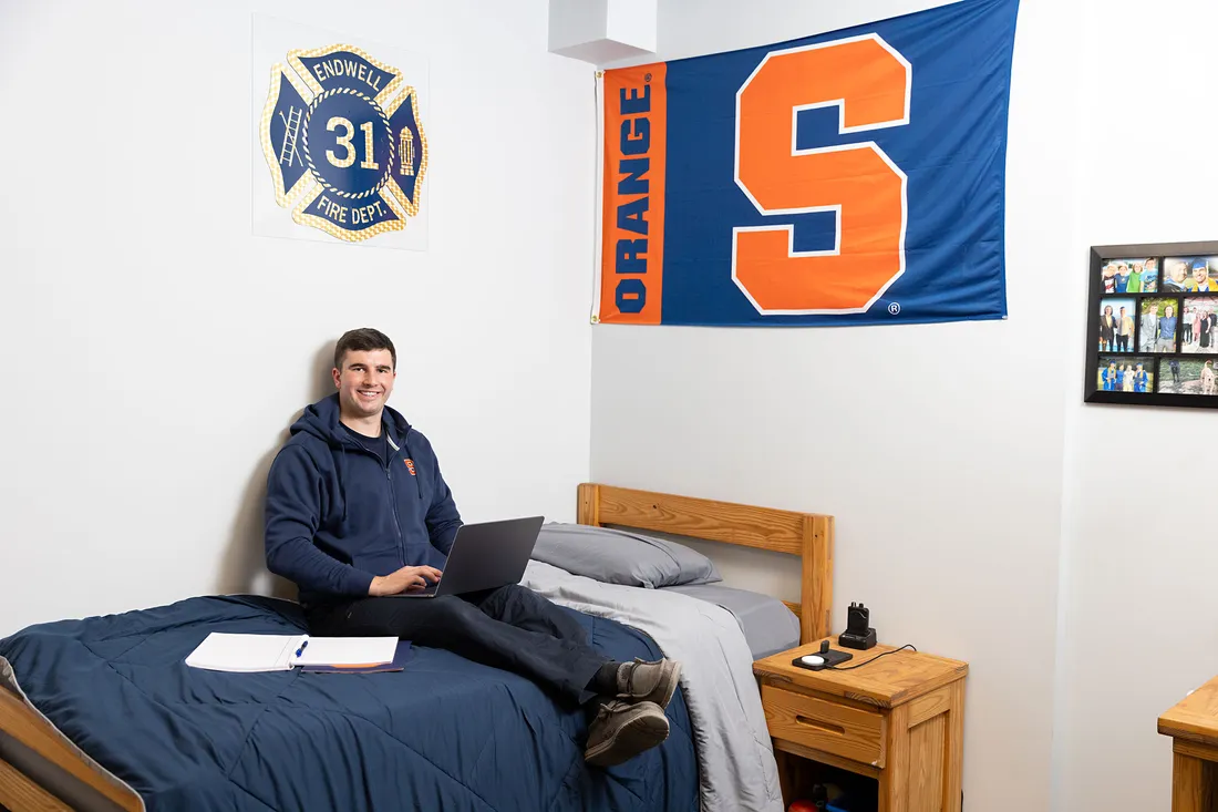 Ryan Derkowski sitting on his dorm bed.