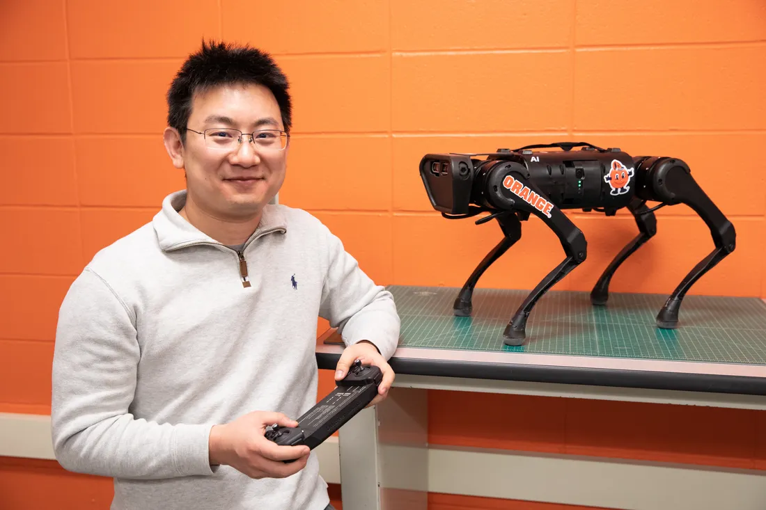 Professor holds controller in front of robotic dog.