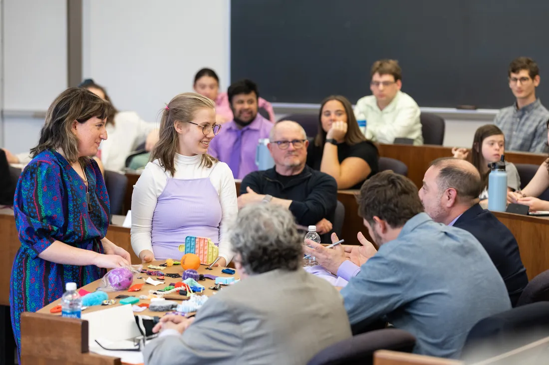 A classroom with two people at the front, teaching a group of people sitting at desks.