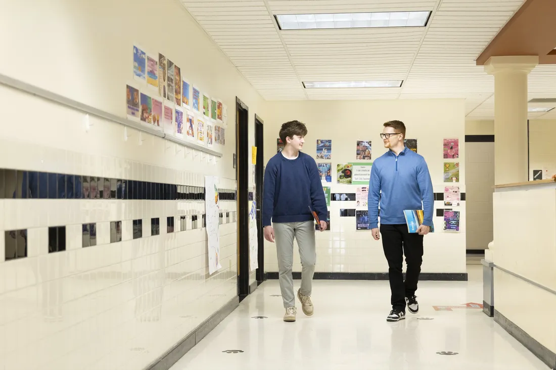 Student Will Baker '27 and alumnus Dylan Gwilt '17 walking down the hallway of STEAM at Dr. King Elementary School.