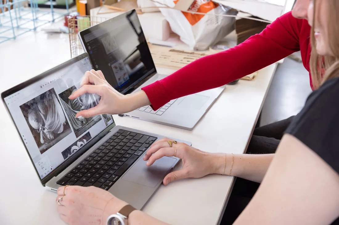 Fingers emphasize graphic on computer screen that two people are looking onto.