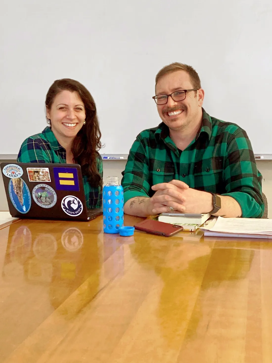 Cara Santino and Evan Weissman sitting at a table with an open laptop, smiling.