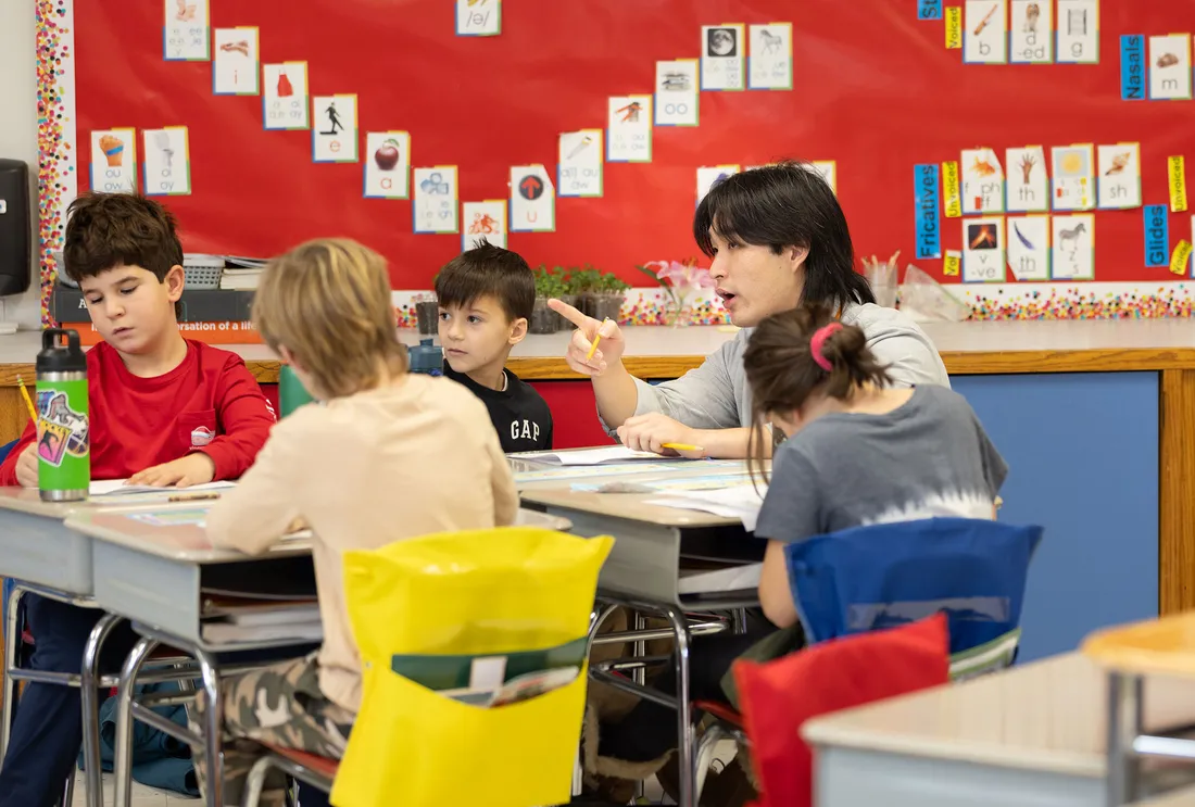 Student teacher sitting with students in a classroom.