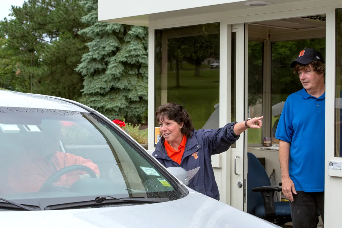 Parking booth attendants direct a car through campus.