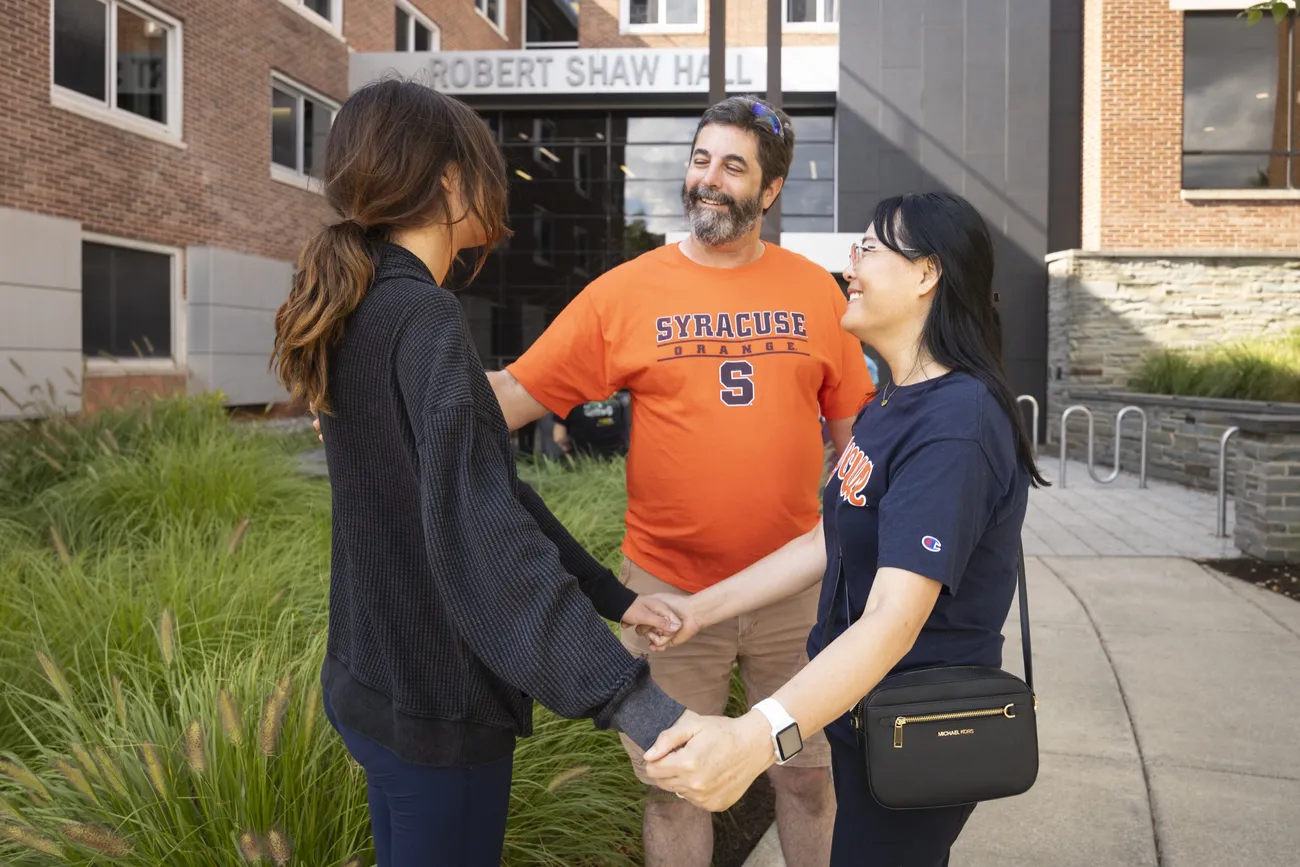 Courtland and Xihui Newman standing outside of Shaw Hall with their daughter, Ashley.
