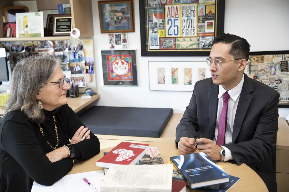 Law student Matthew Yanez sitting at table reading book with professor.