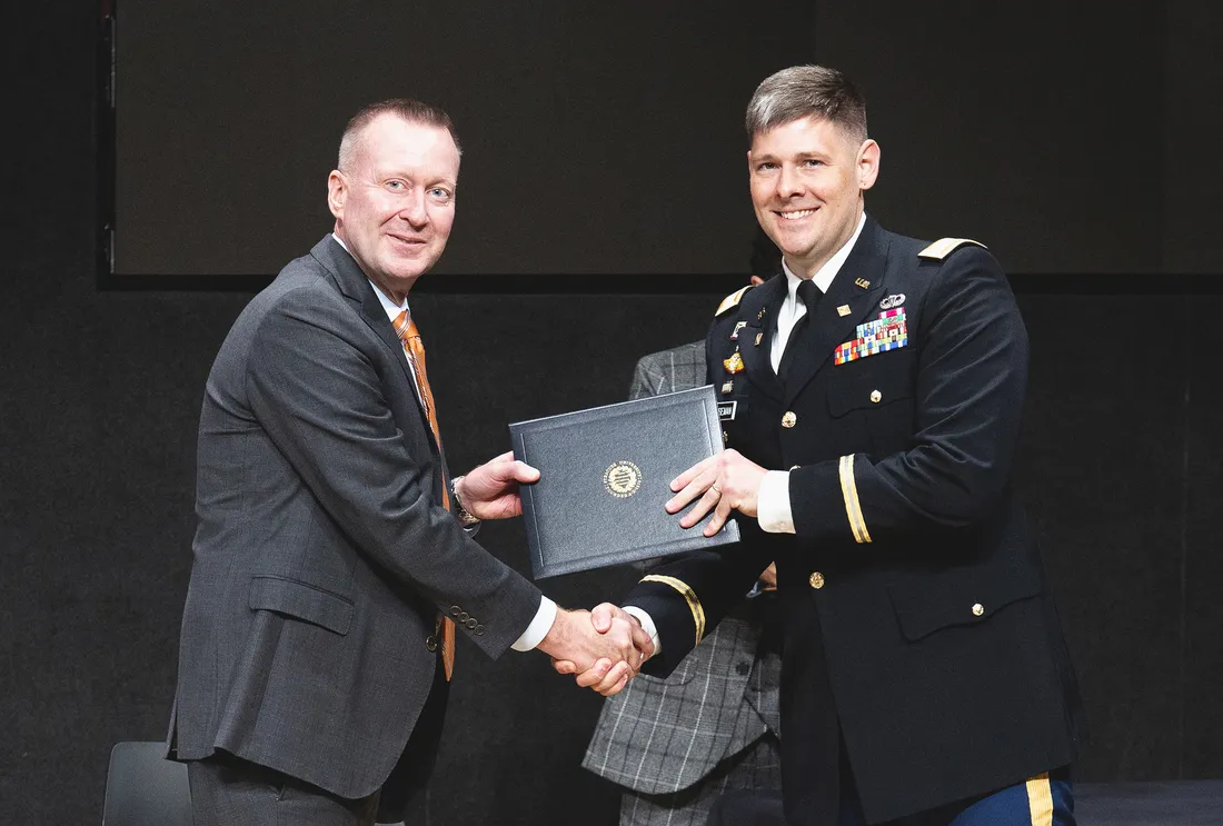 Portrait of Haynie shaking Huseman's hand as Huseman receives an award.