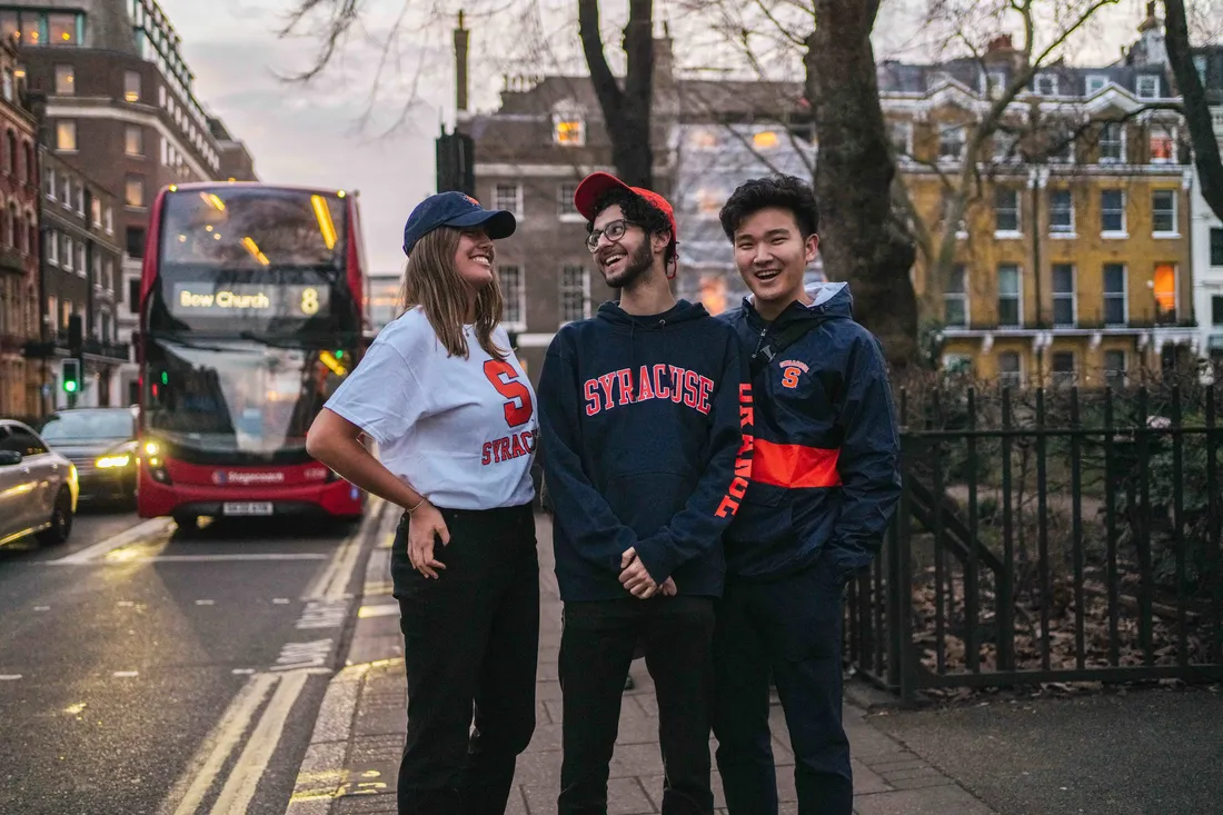 Three students on a London street smiling and laughing.