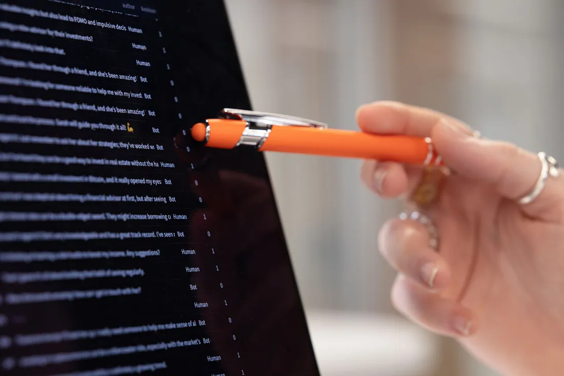 Hand using pen to point to data on a computer screen.