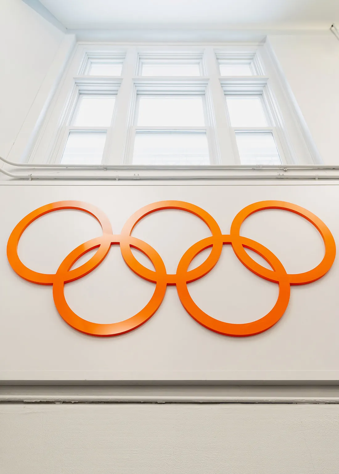 The Olympics Rings in the color orange on the side of a wall.
