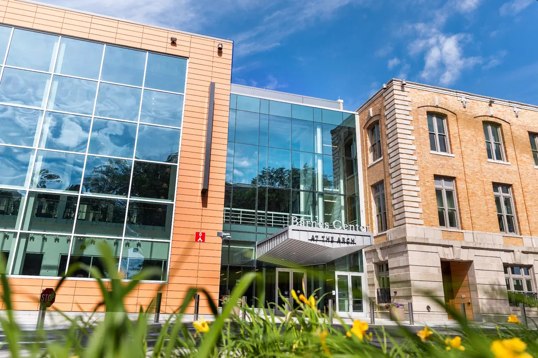 Barnes Center main entrance, with blue sky and trees reflected in the glass around the door.