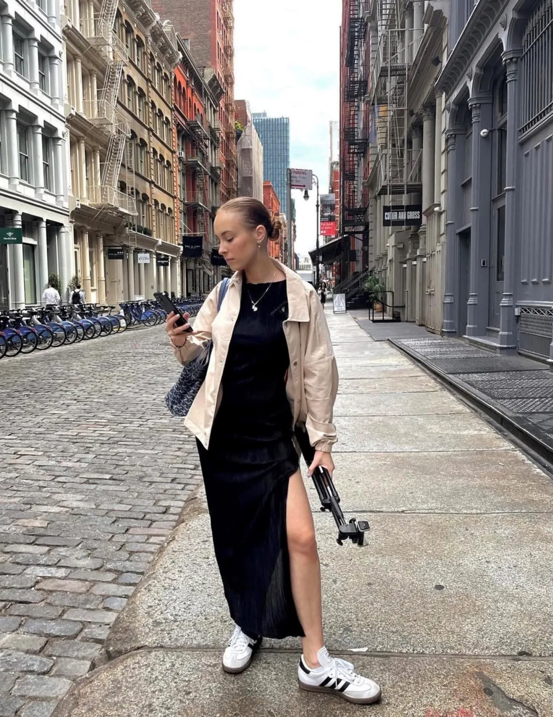 Liv Pines '24 posing in the street with a camera and a tripod.