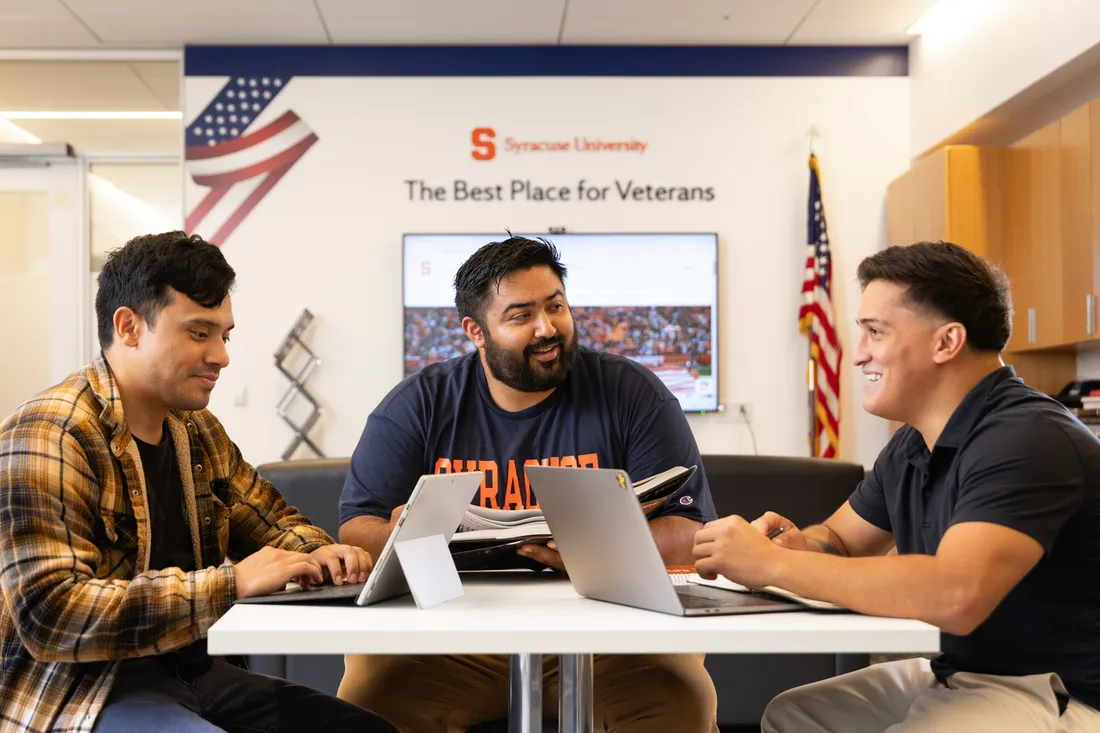 Three students sitting at a desk and talking.