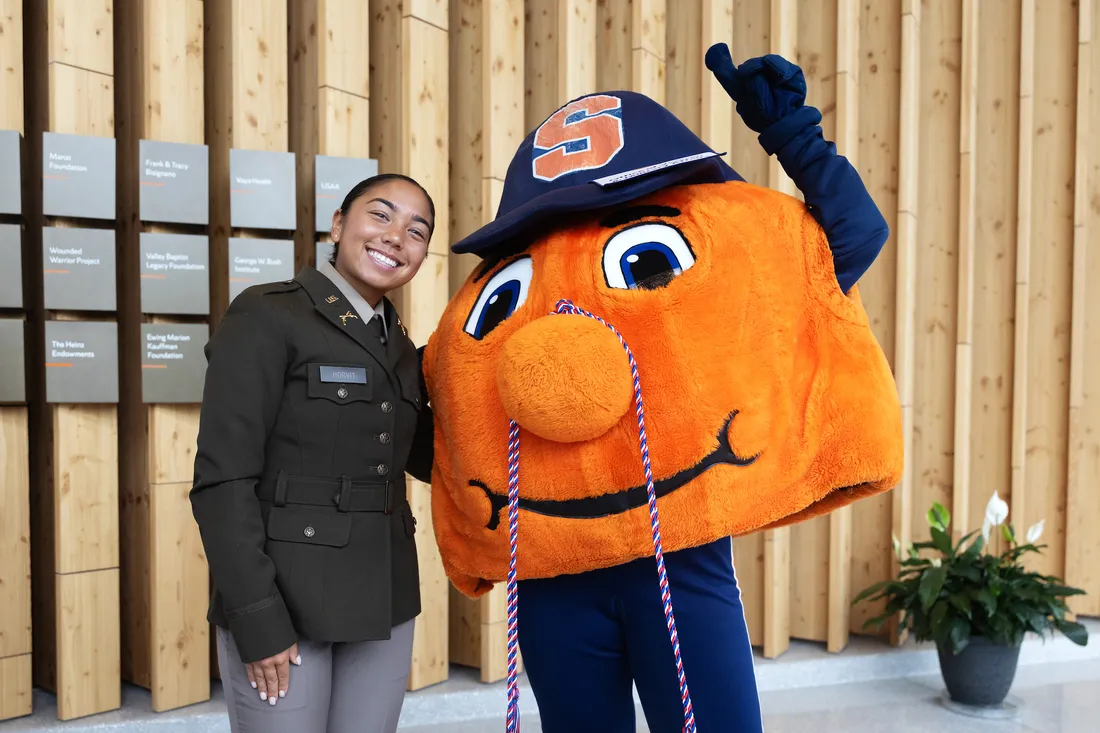 Army ROTC cadette standing and smiling with Otto.