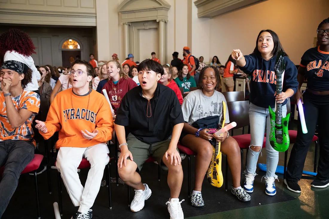 Students interact with presentation game in large assembly.