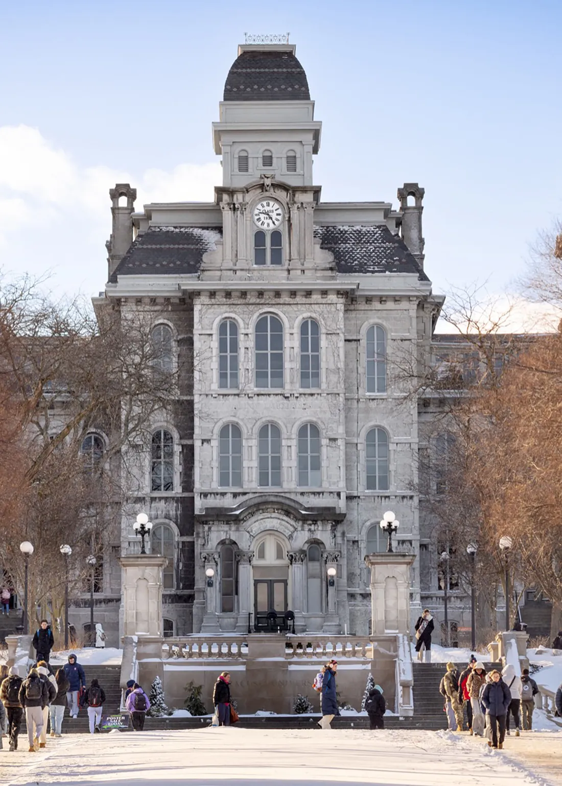 The exterior of Syracuse University's Hall of Languages during a sunny winter day, with students walking outside of the building,