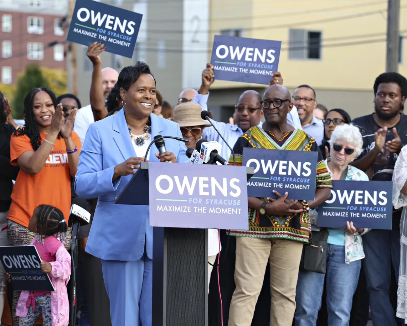 Mayor Sharon Owens '85 standing at a podium speaking during her mayoral campaign, surrounded by supporters.