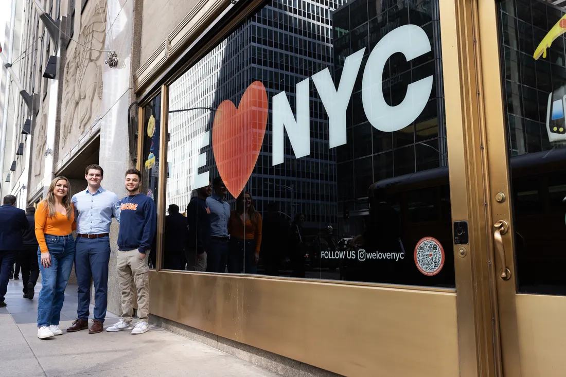 Three people standing in front of an "I love NYC" sign.