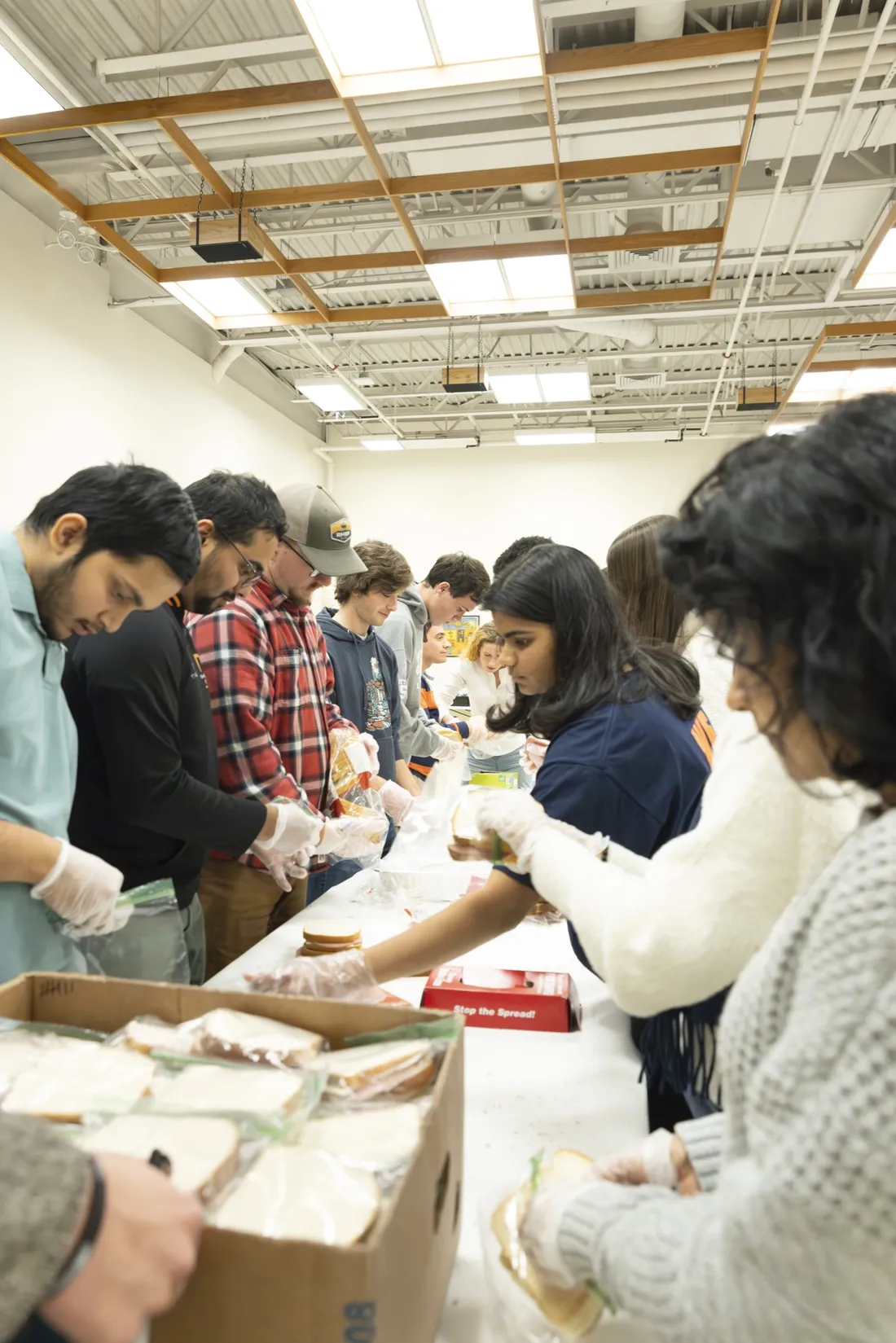 A line of students working together to assemble sandwiches for local food pantry.