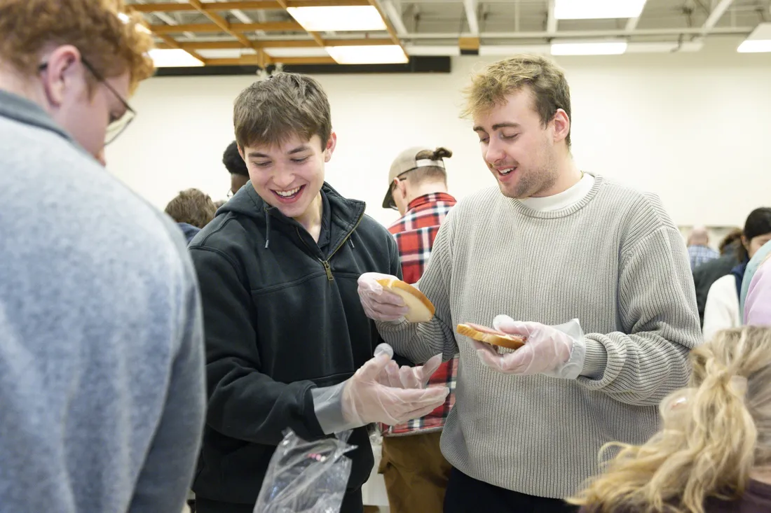 Two students working together to make sandwiches for Slice of Hope's annual sandwich making campaign.