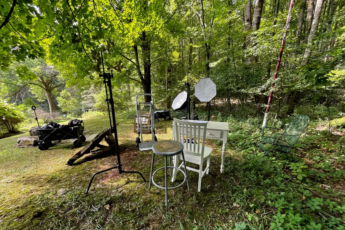 Wide photo of photography equipment and furniture scattered around in nature.