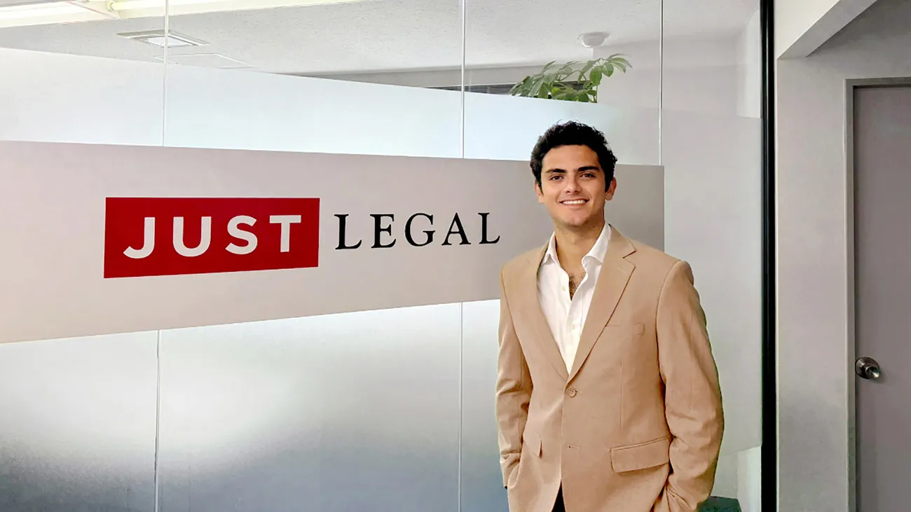 Person standing in front of sign wearing a suit.