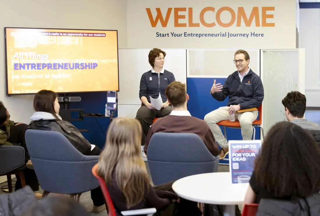 Orange Tank participant Ava Lubkemann '27 sitting with Peter Forsgren '97 and speaking to a group of students.