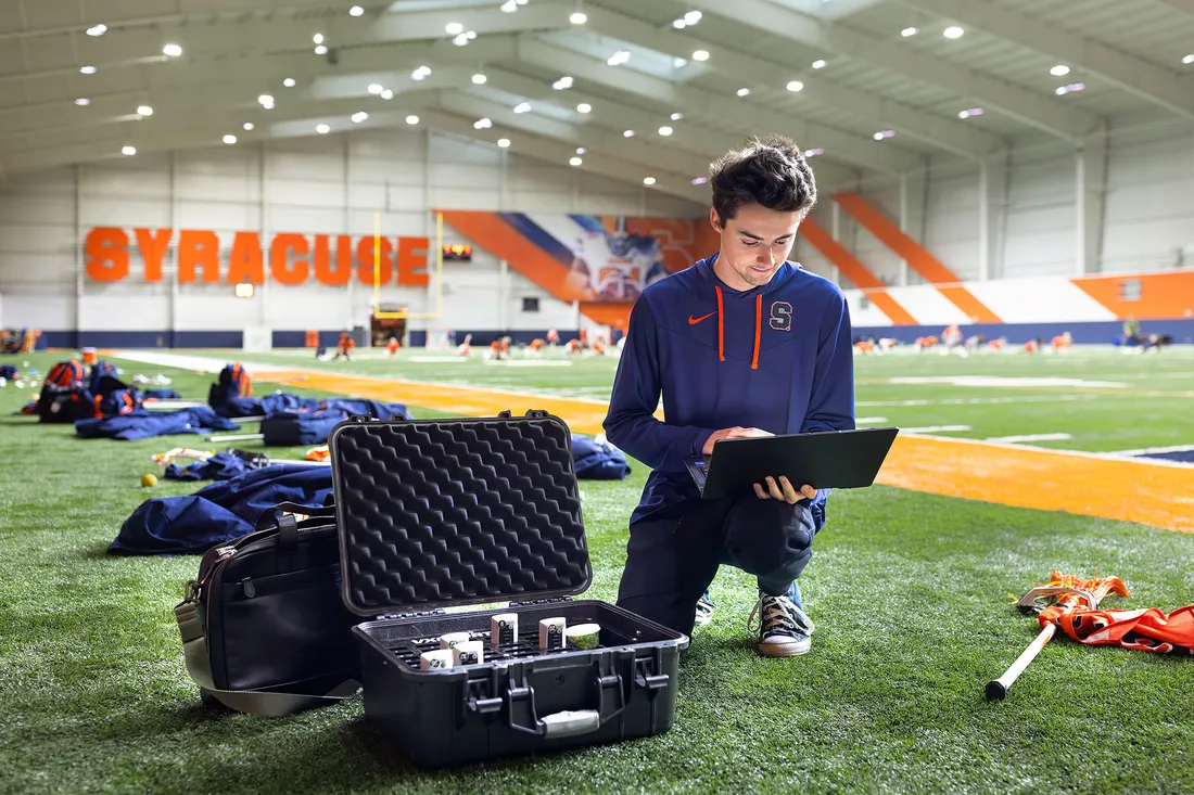 Student working on laptop in lacrosse stadium.
