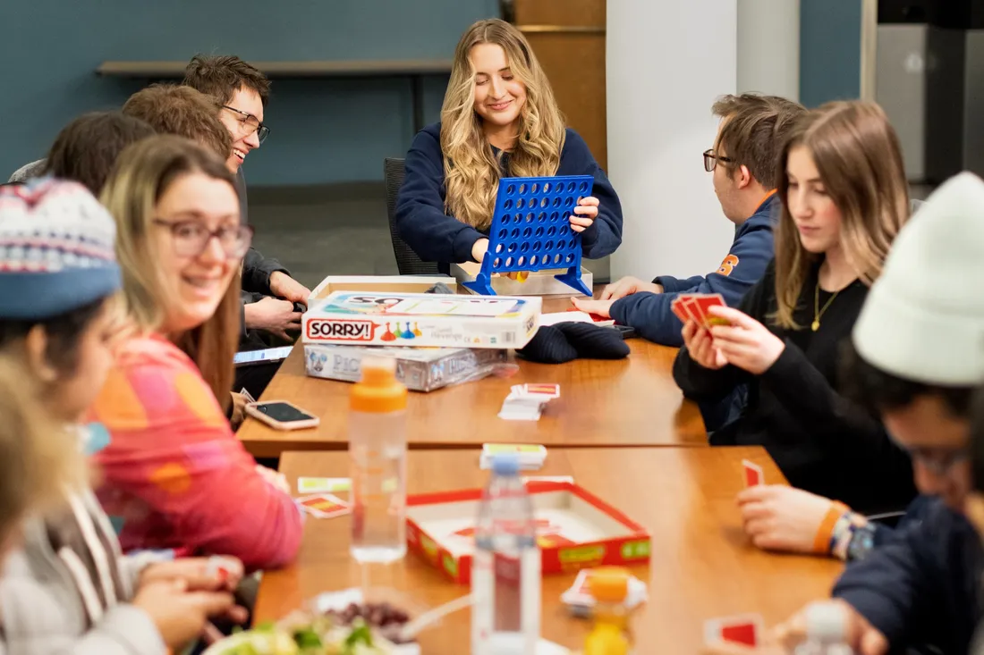 Students in sitting at a table playing different board games together.