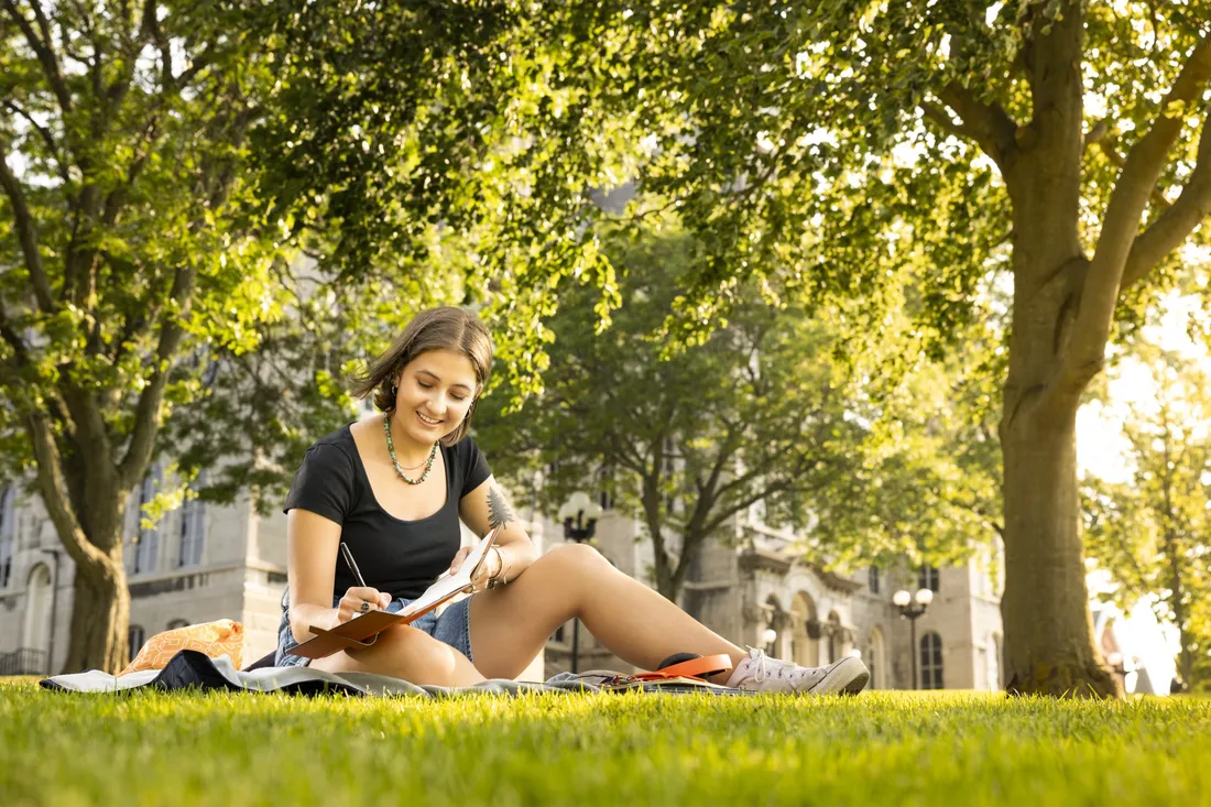 Student Caiyan Power Bass sitting on the grass in the summer.