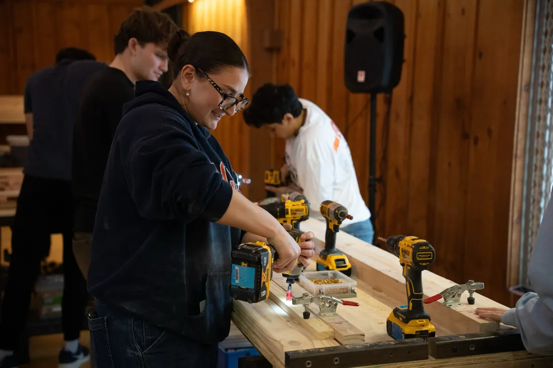 Student using a power drill to build the foundation for a bed.