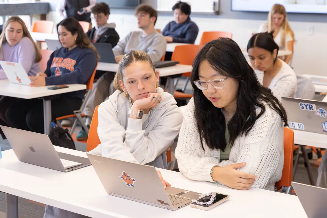 Students sitting at desks looking at a computer.