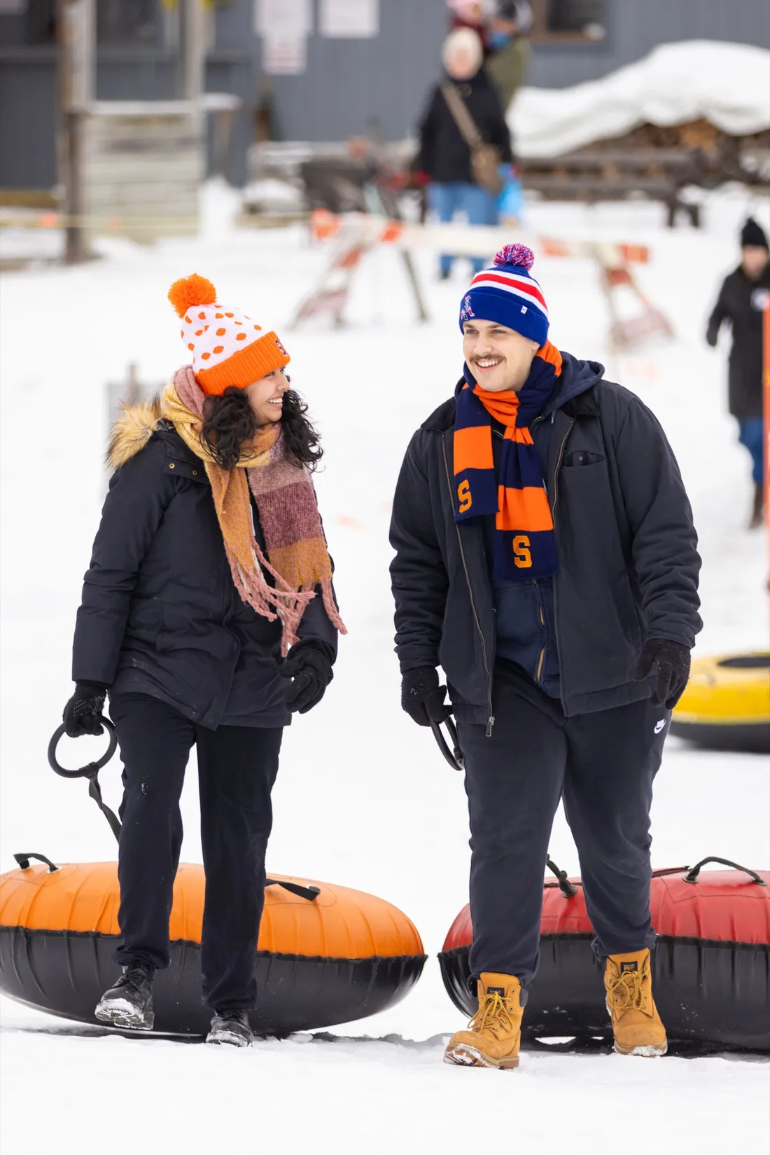 Two students talking and pulling snow tubes.