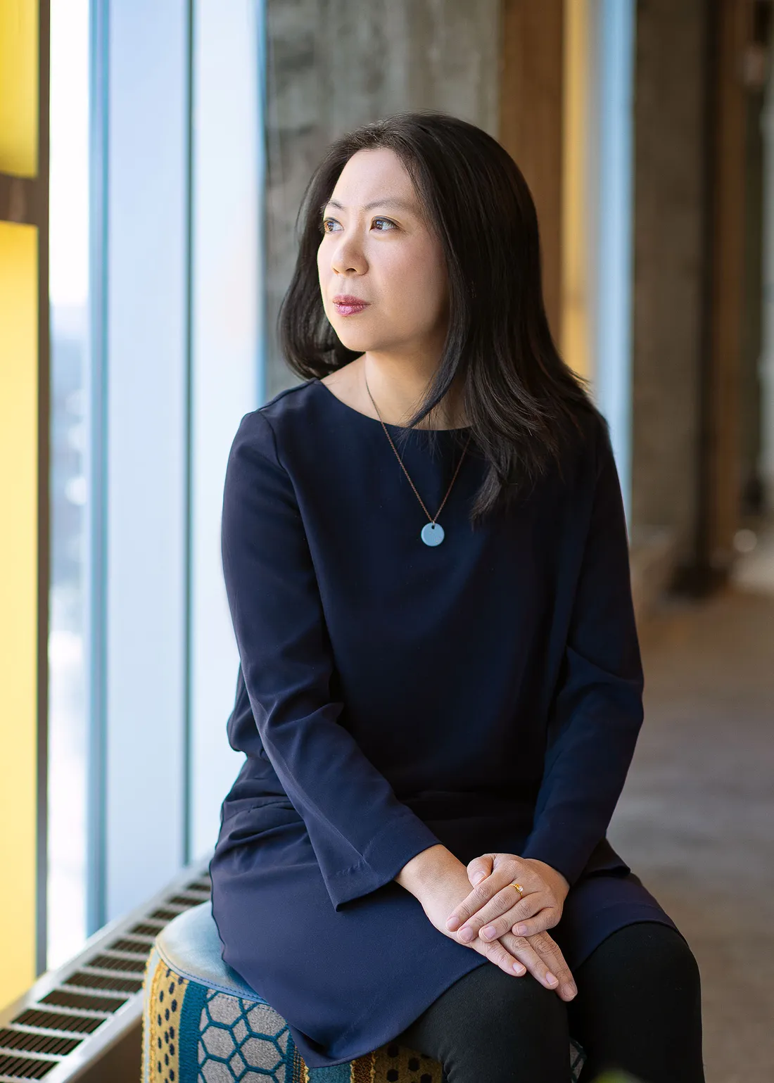 BaoBao Zhang looking out a window in a black long sleeve shirt.