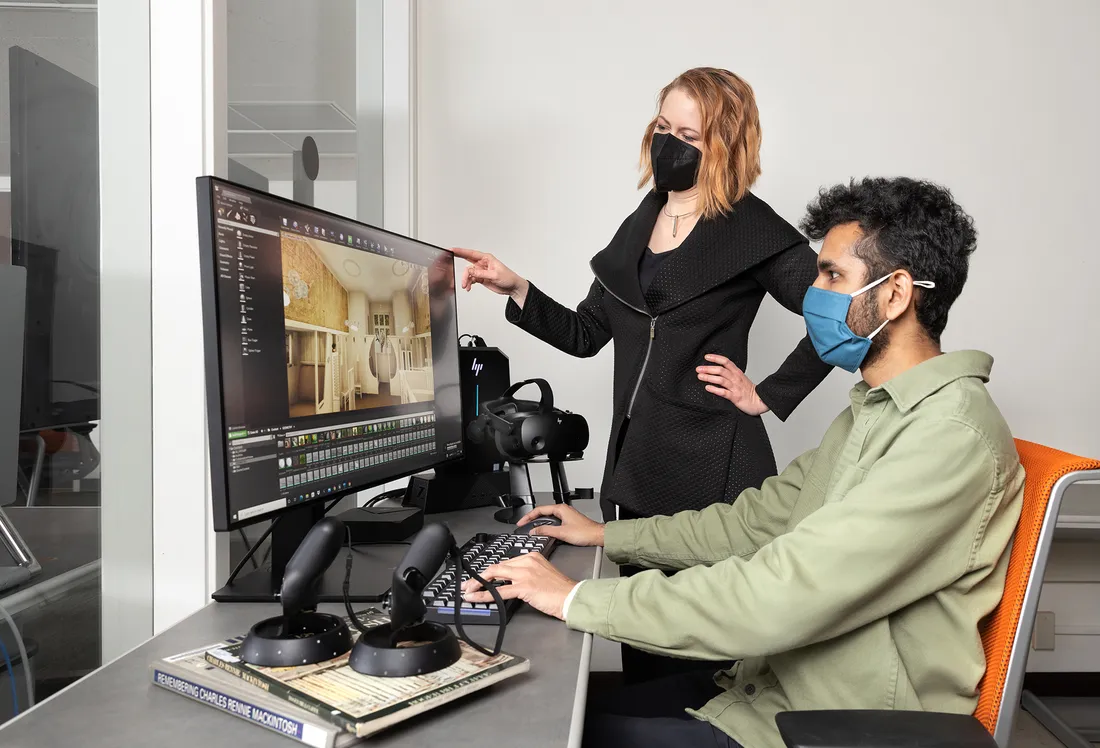 Professor Amber Bartosh assisting a student working on a computer.