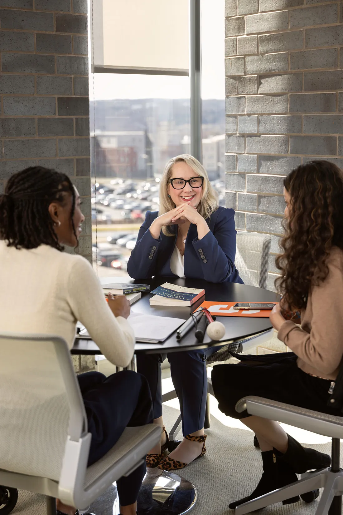 Kat MacFarlane talking with two students at a table.