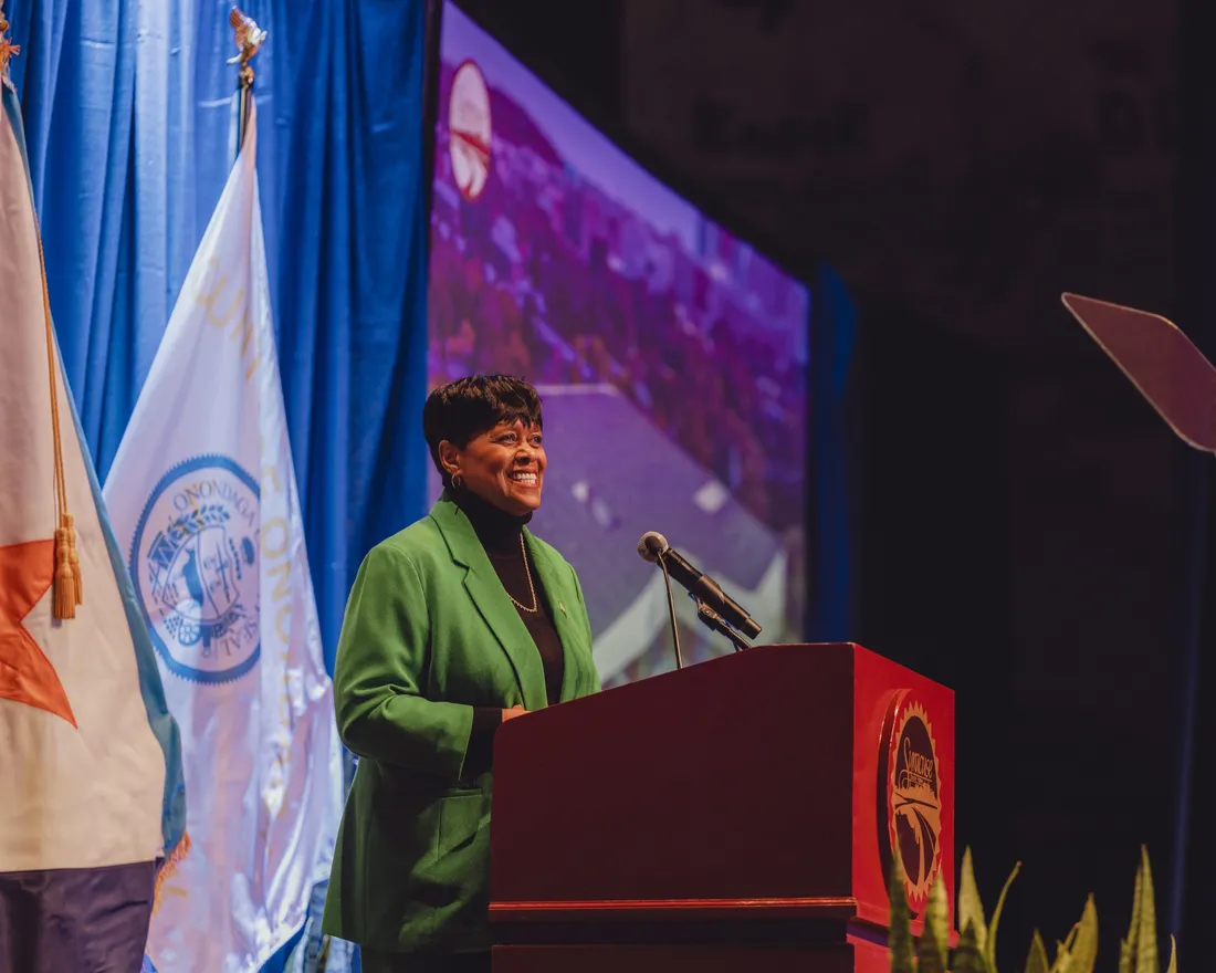 Sharon Owens ’85, standing at a podium, talking.