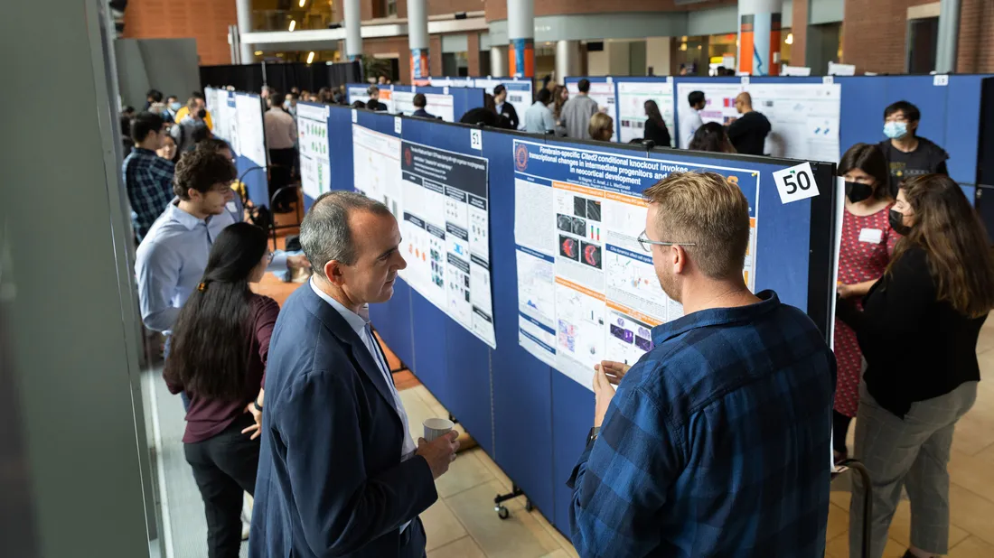 Photo of a large group in atrium looking at scientific posters, taken from a high angle.