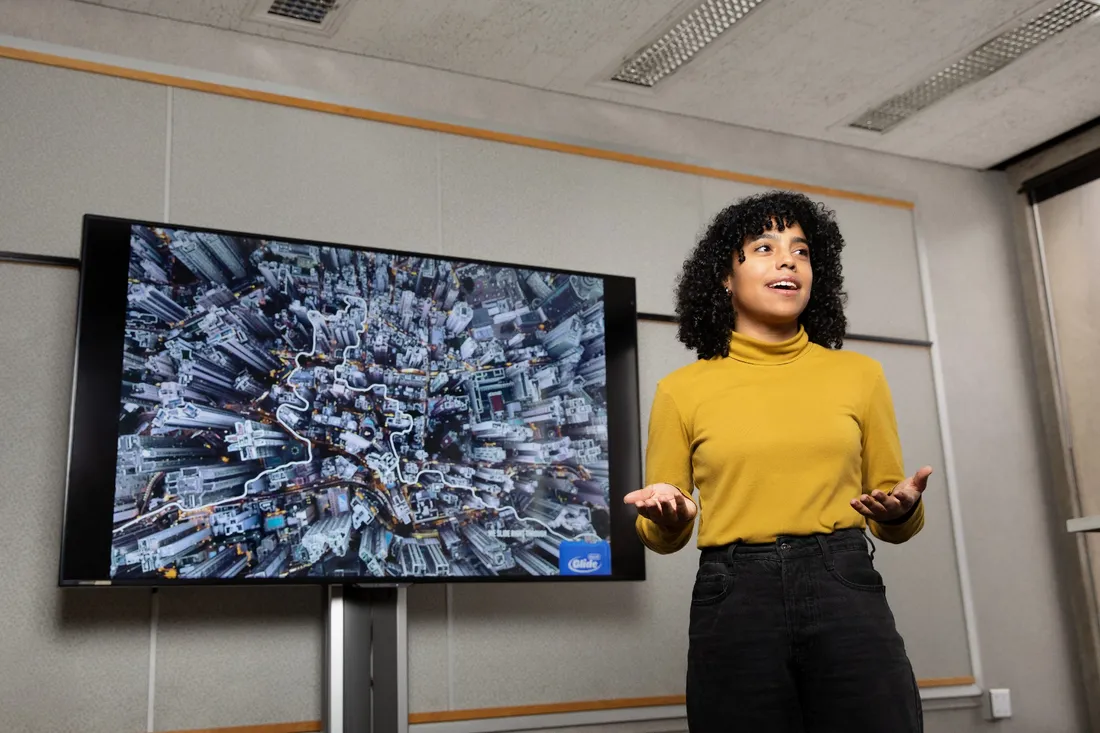 Nico Aramboles stands in front of a screen with art displayed on it.