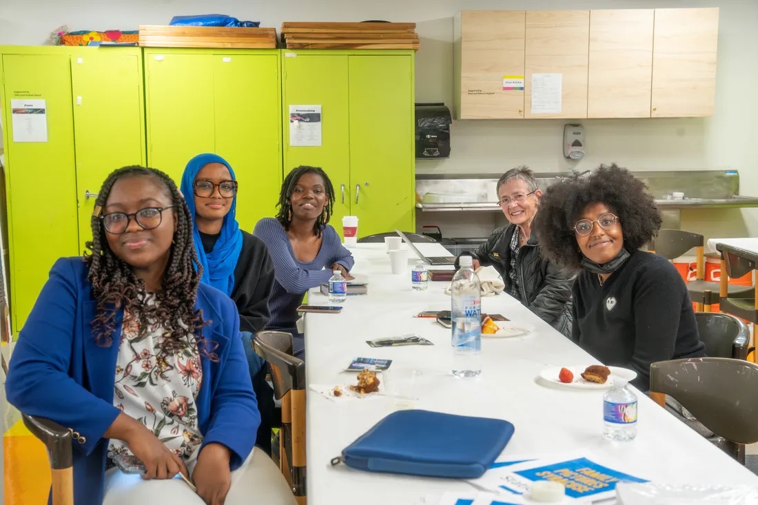 Five people sitting at a table smiling.