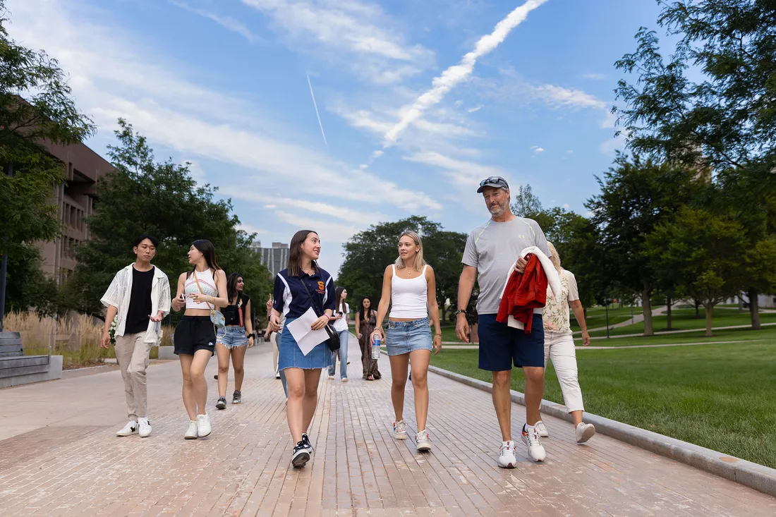 International students walk outside and smile.