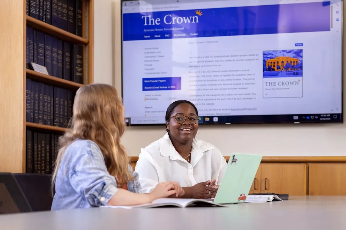 Two students are sitting together at a table at the Crown Editorial Journal.
