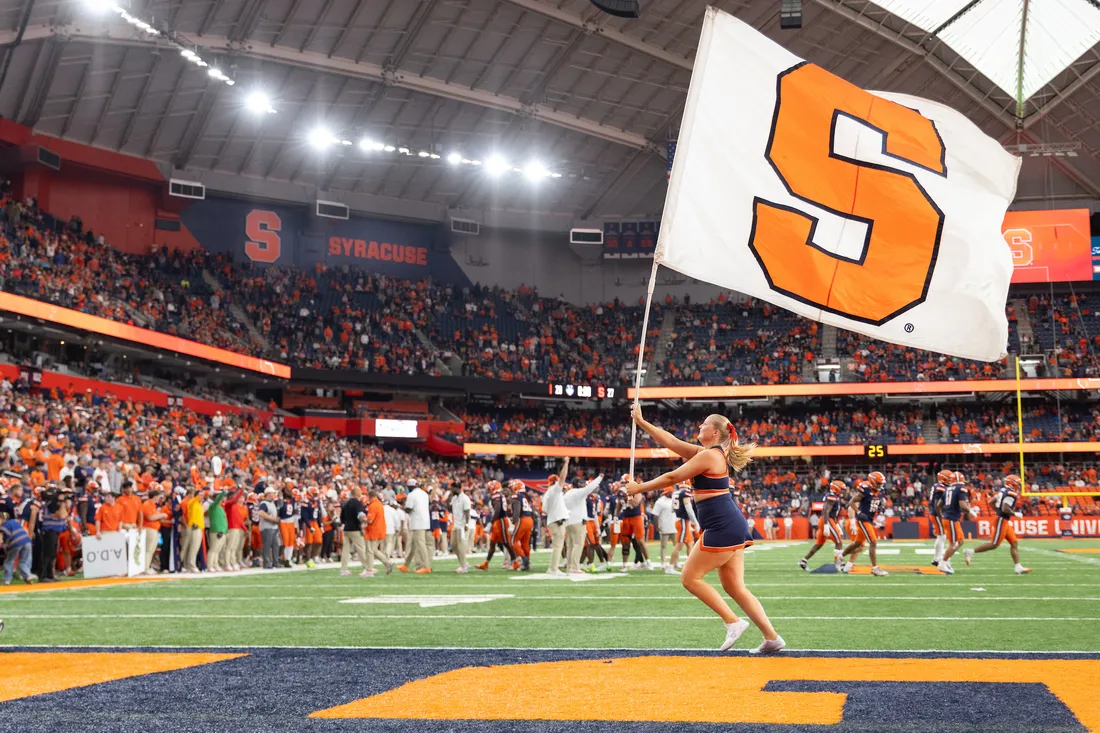Student waiving a Syracuse University flag in the JMA Wireless Dome.