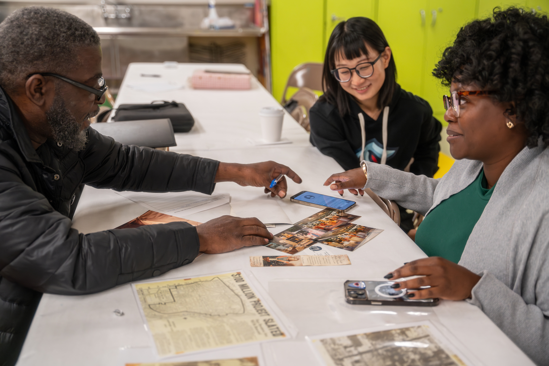 Syracuse University volunteers work with woman to scan photos as part of the Family Pictures program.