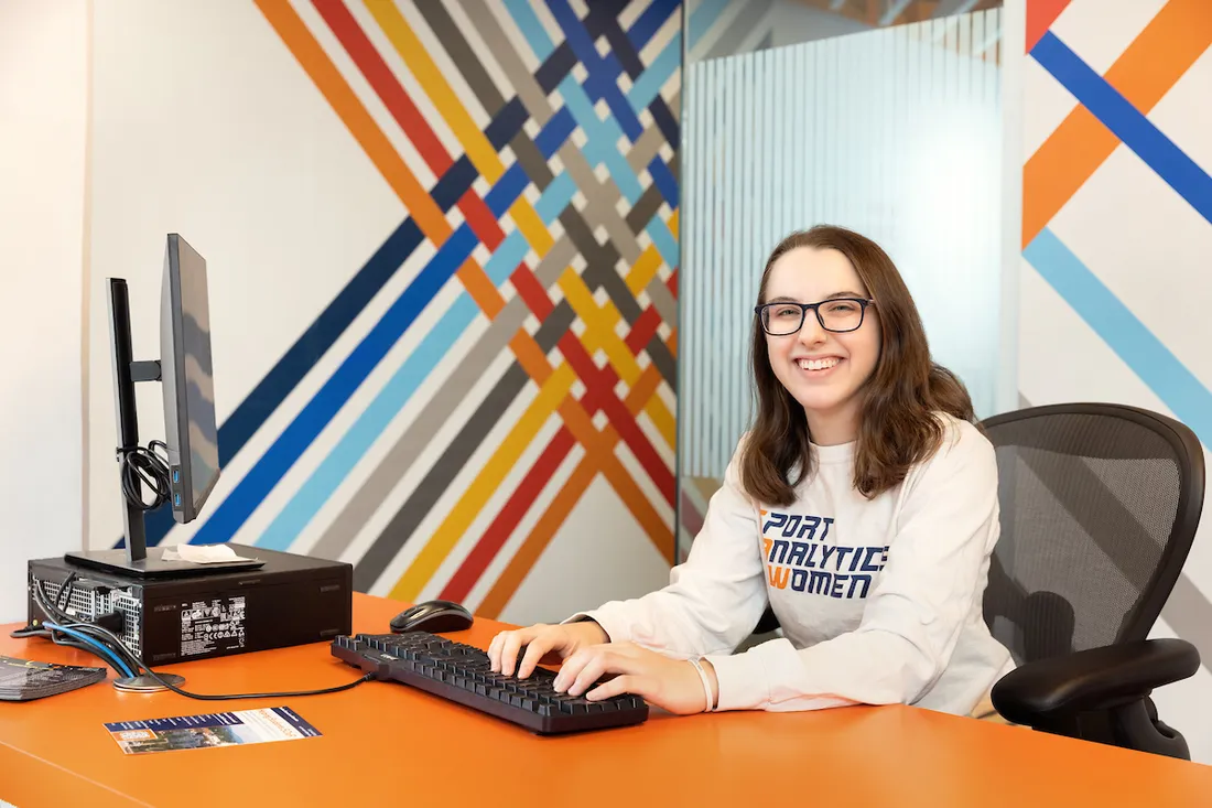 Student worker on computer at a front desk.